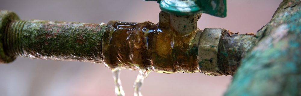 Water leakage at the junction of the water shut-off valve and pipe. Technical problem of rusty pipes in the garden.