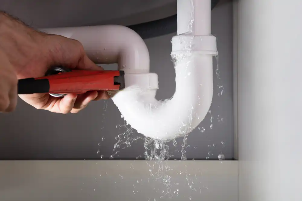 Close-up Of Male Plumber Fixing White Sink Pipe With Adjustable Wrench